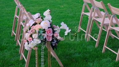 花束和绿色草地上的白色木制空椅子。 婚礼装饰。
